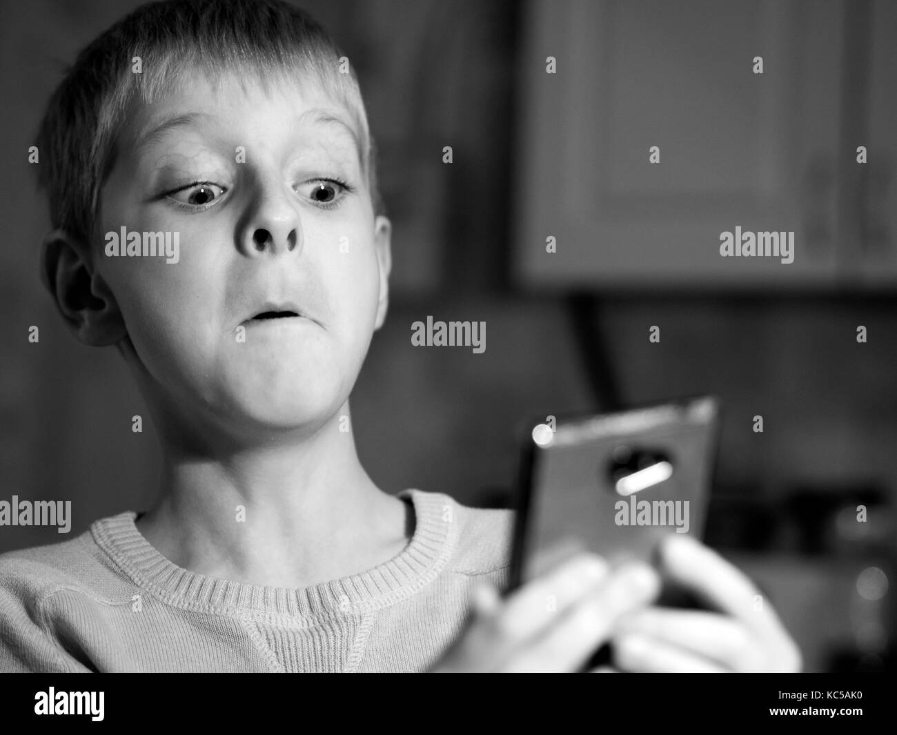 Surprised caucasian boy  with mobile phone. Black and white Stock Photo