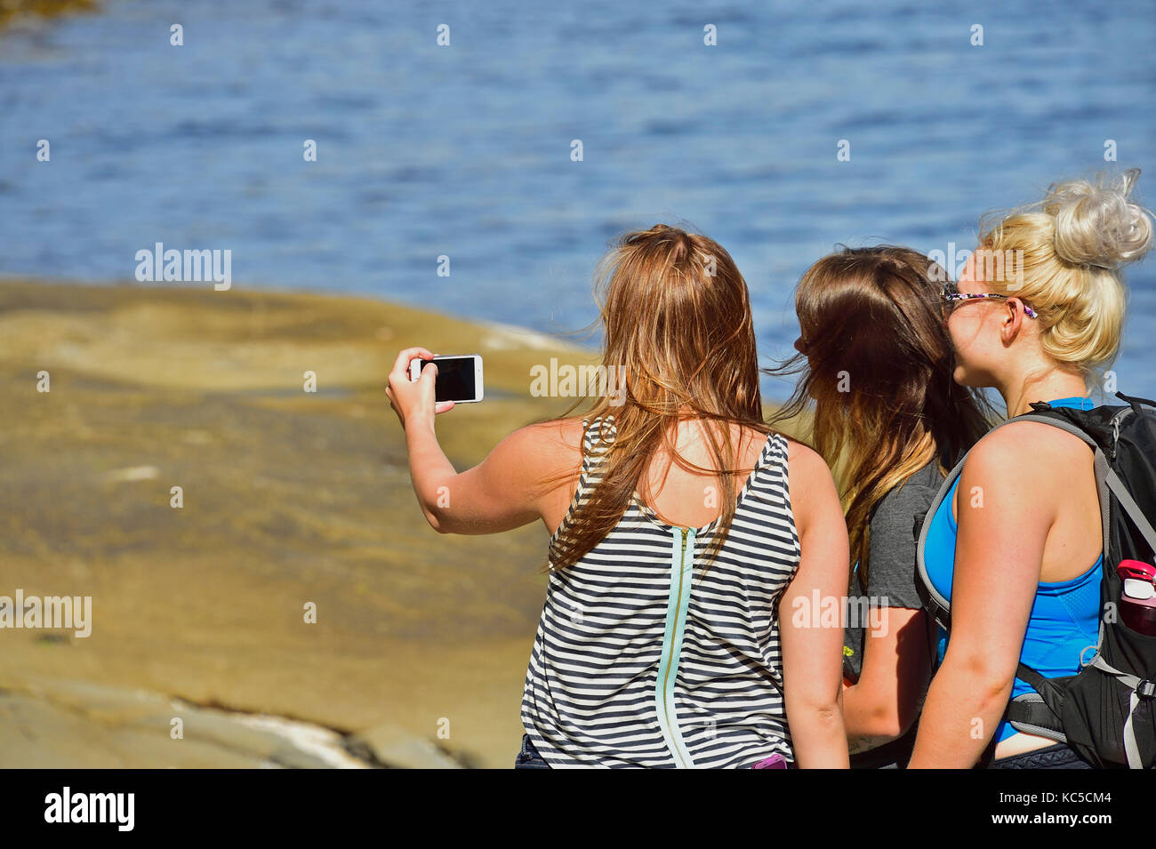 Three girls taking a selfie on the rocky beach on Vancouver Island British Columbia Canada. Stock Photo