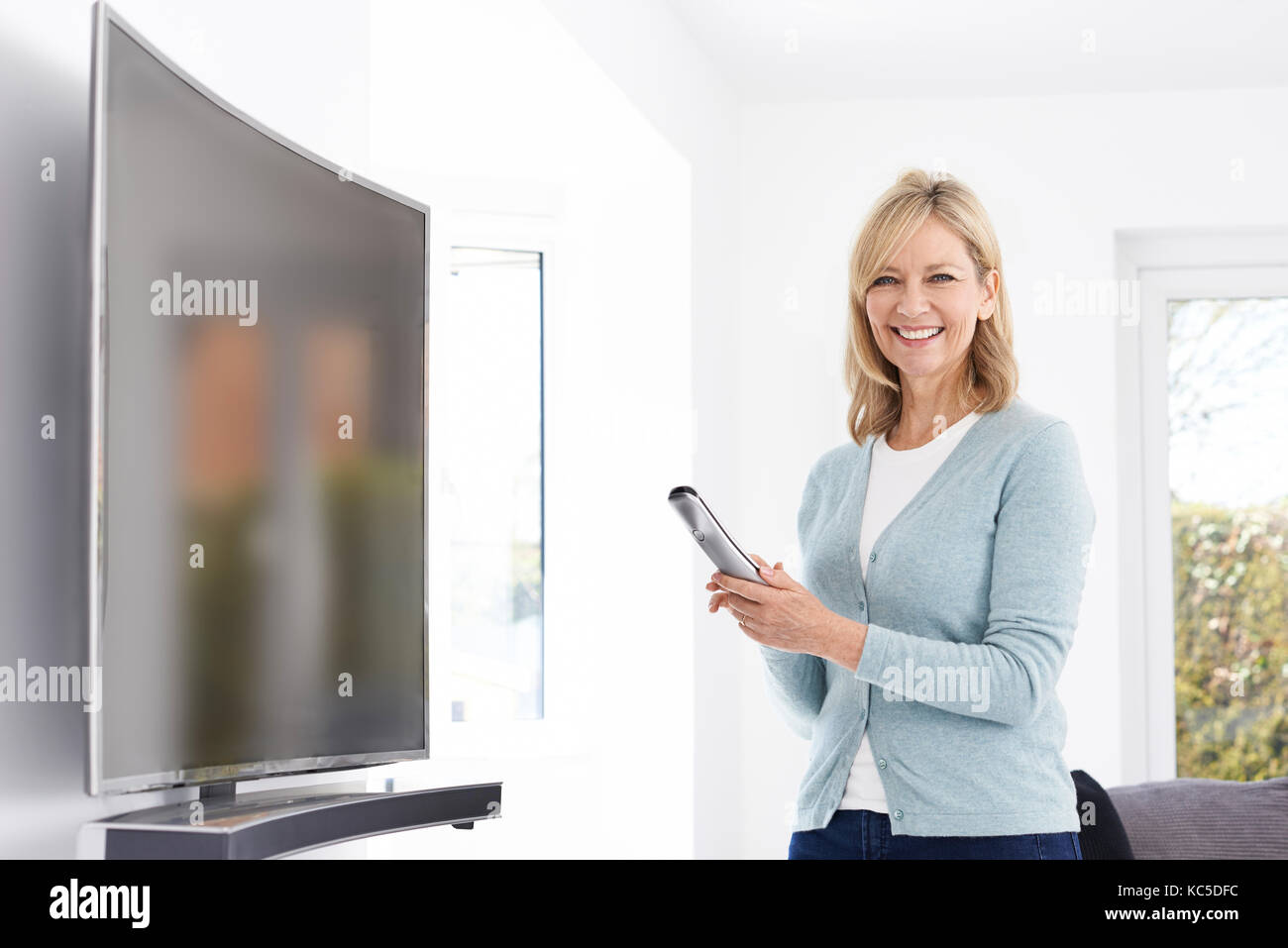 Mature Woman With New Curved Screen Television At Home Stock Photo