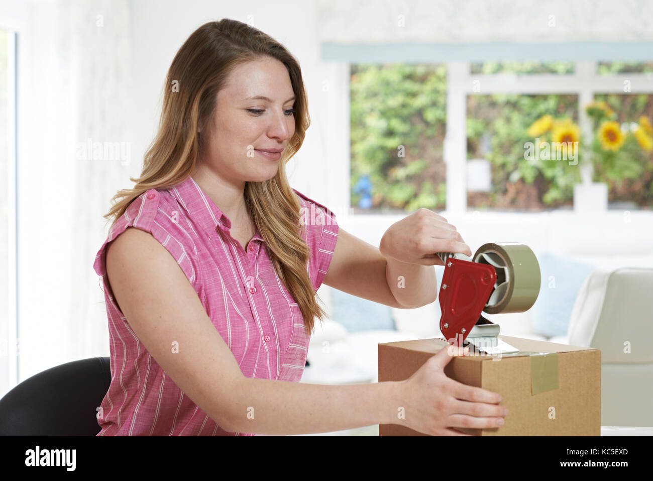 Woman At Home Sealing Box For Dispatch Stock Photo