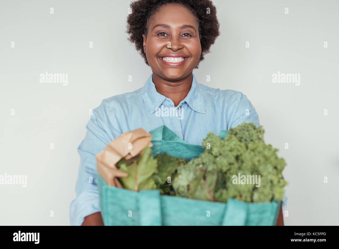 Smiling young African woman holding a bag of groceries Stock Photo