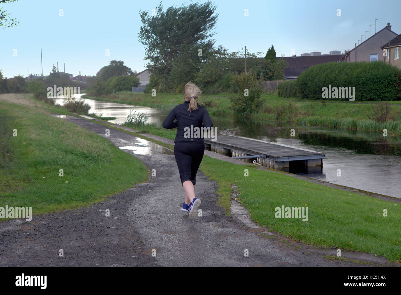 solo female woman runner jogger running Forth and Clyde Canal blonde Caucasian Stock Photo