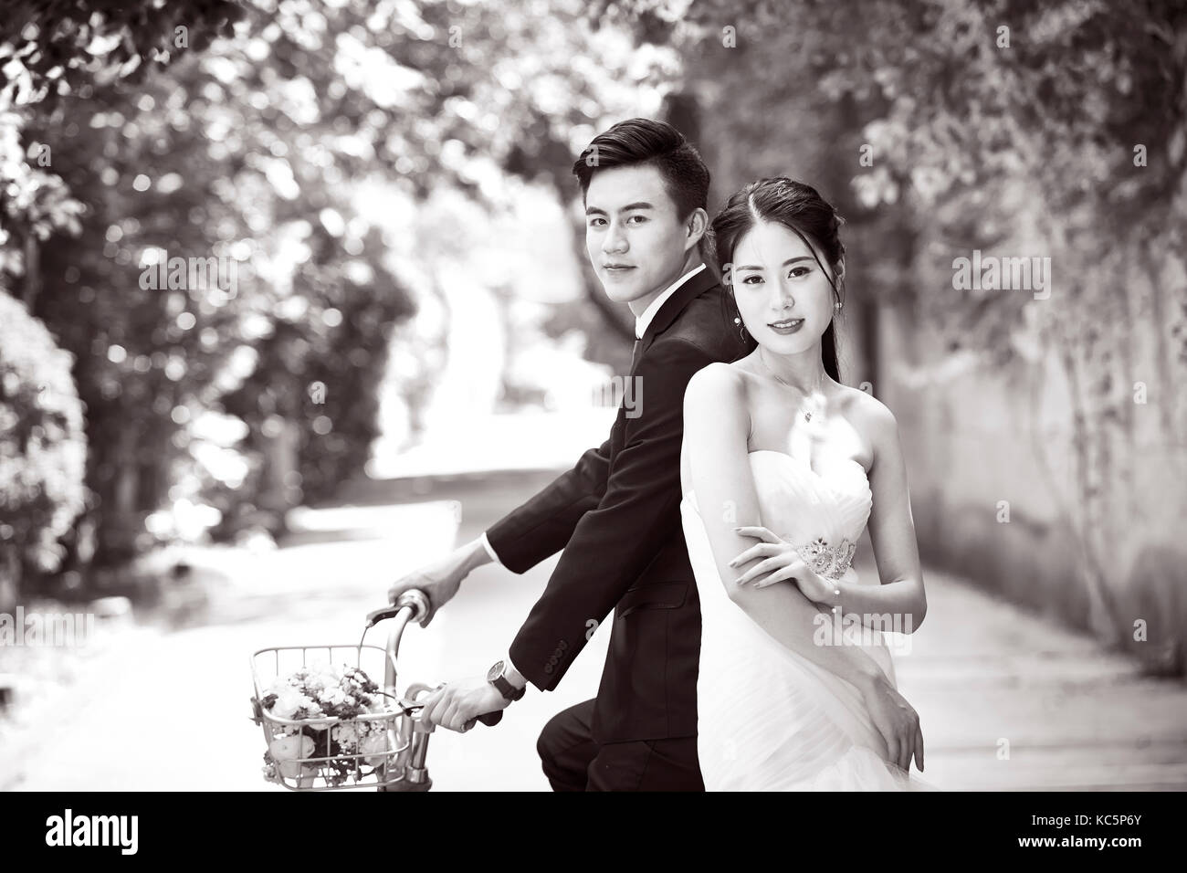 newly-wed asian bride and groom taking picture with a bicycle, black and white. Stock Photo