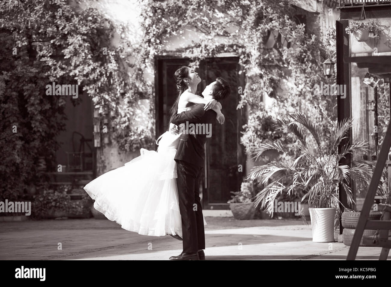 asian newly wed bride and groom celebrating marriage outside a building, black and white. Stock Photo
