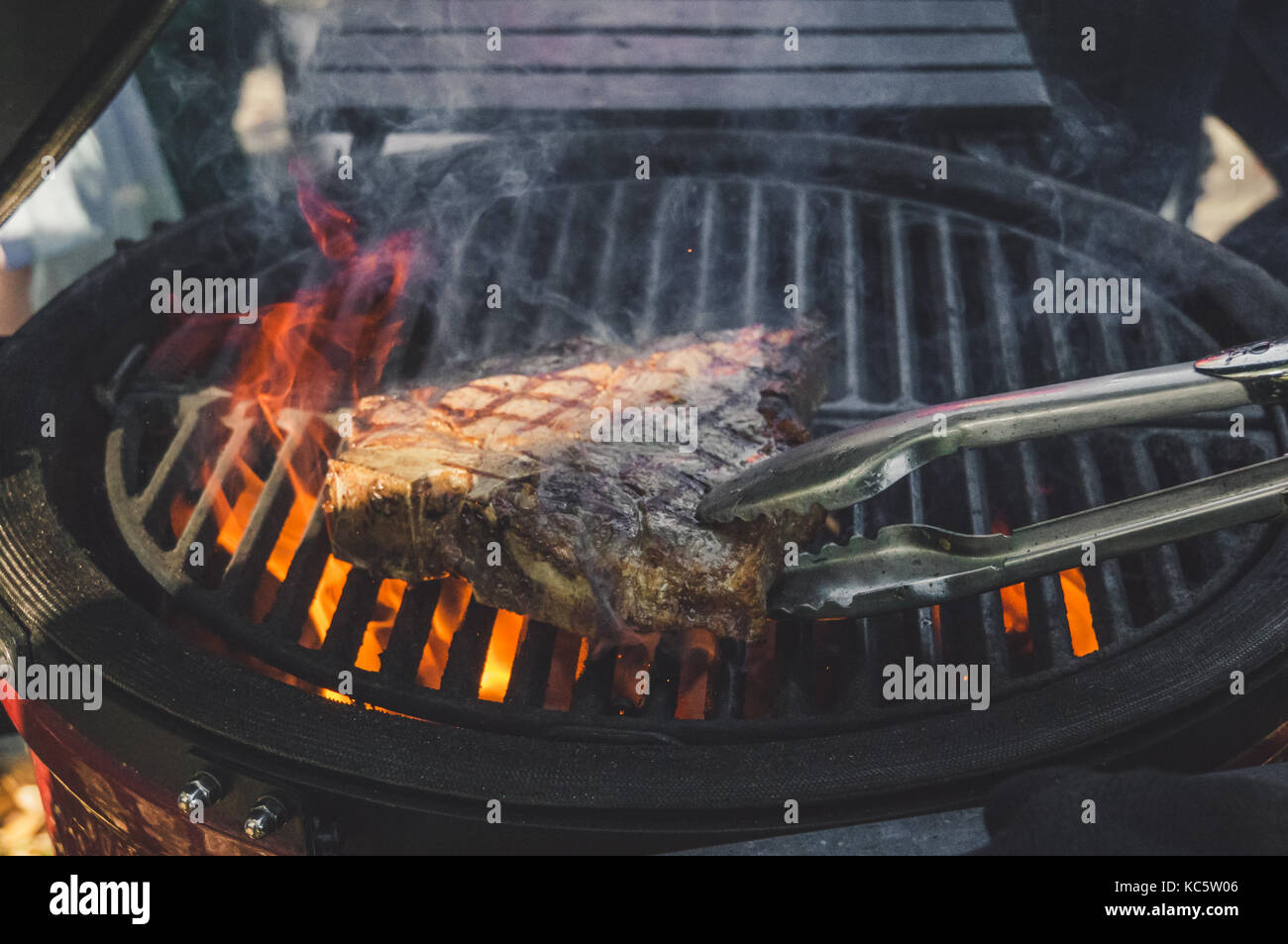 A piece of meat in flame. . The cook flips a piece of meat beef on the
