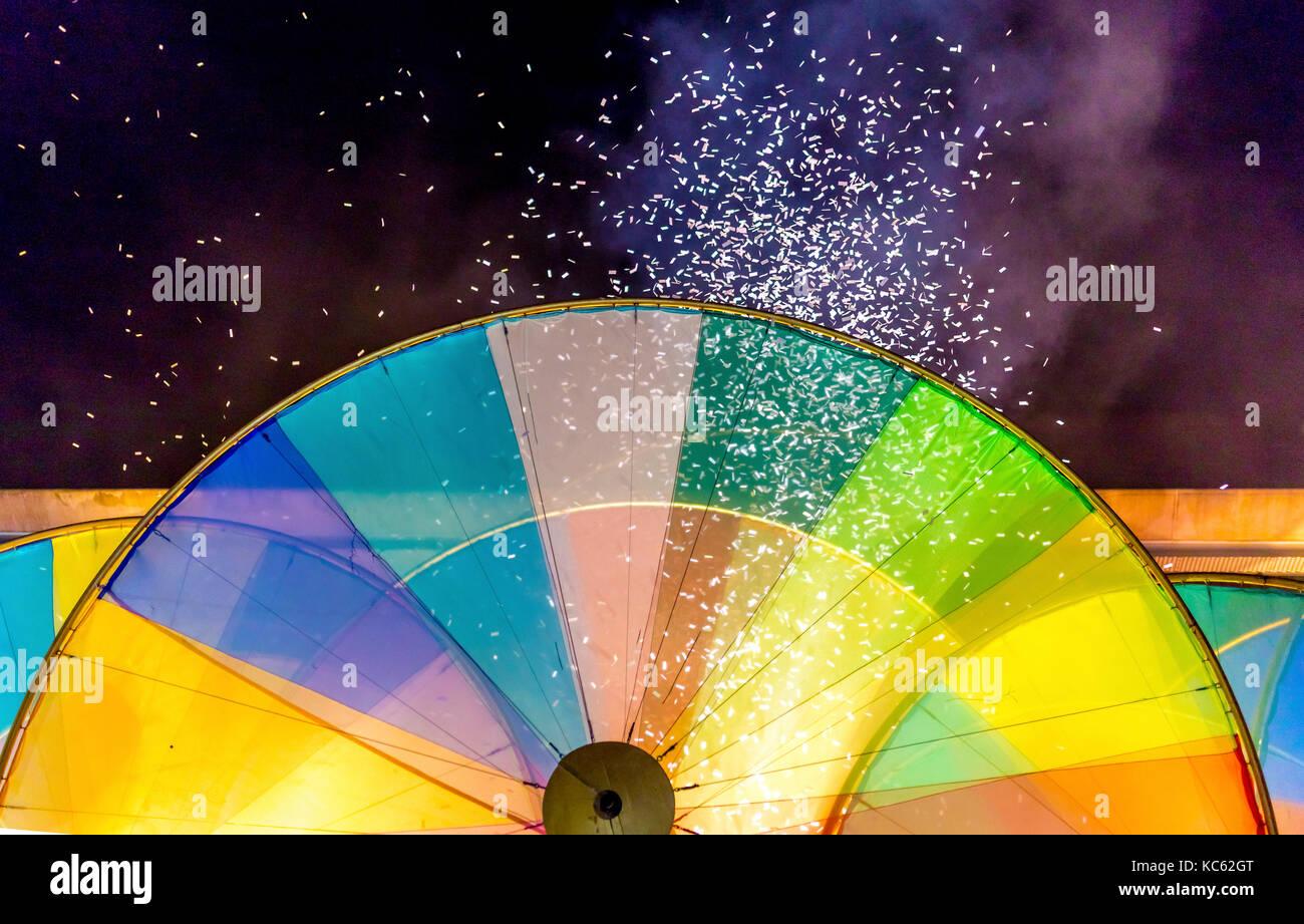 Confetti cannon blasts confetti into the night sky above a colour wheel