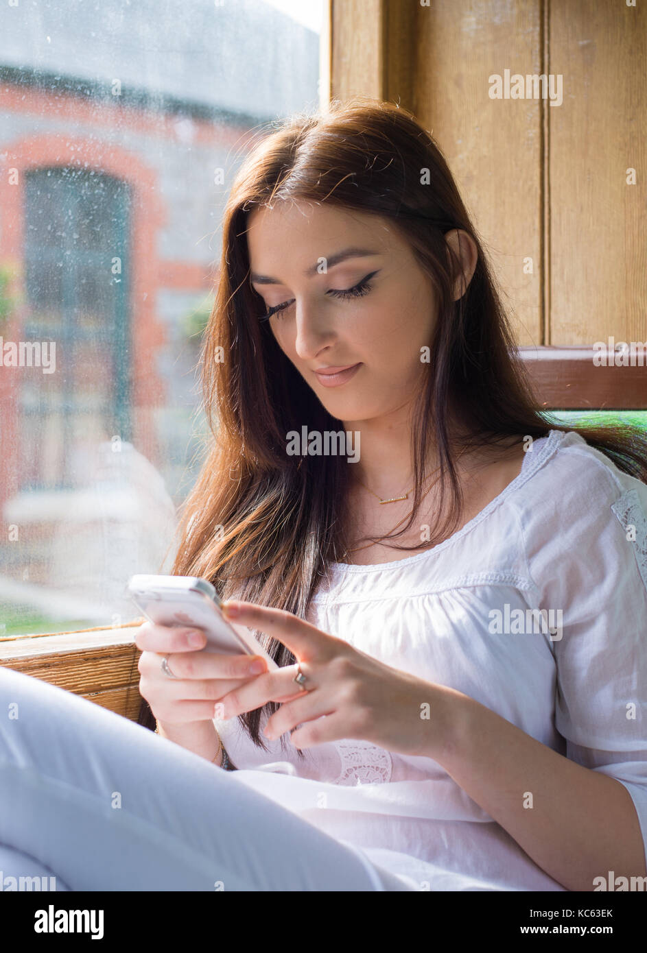 Pretty young lady on an old train using her cellphone Stock Photo