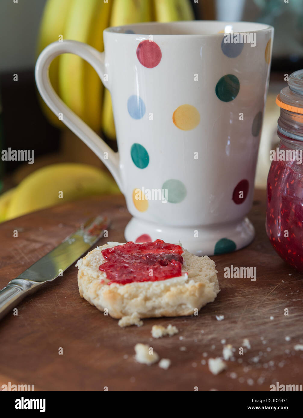 Scone with raspberry jam and spotty mug Stock Photo