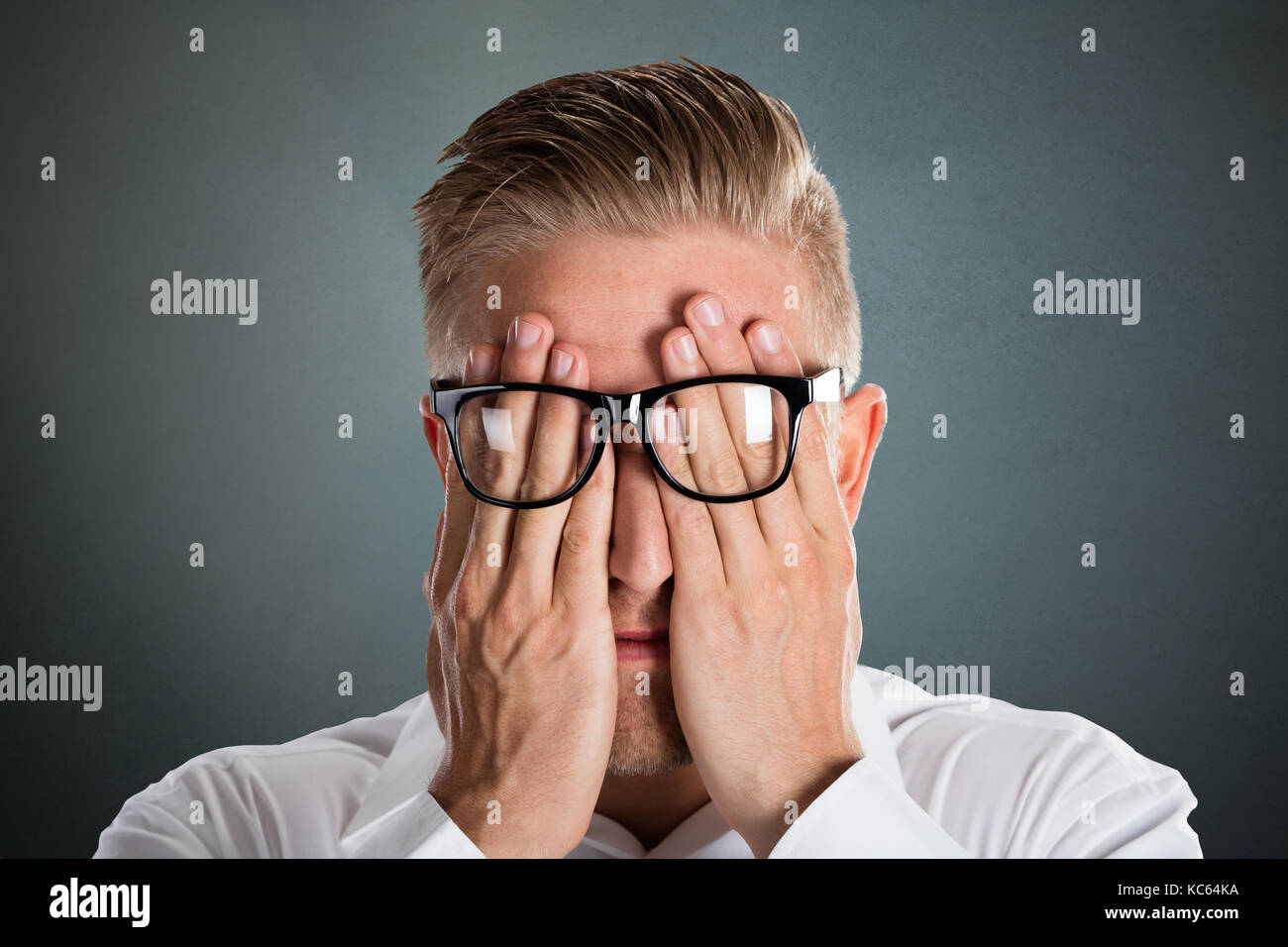 Man's Hand Over The Face With Eyeglasses Over Grey Background Stock Photo