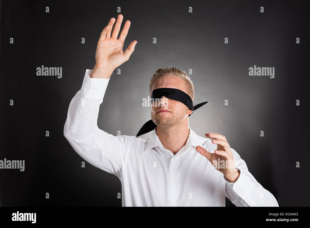 Young Blindfolded Confused Businessman Against Grey Background Stock Photo