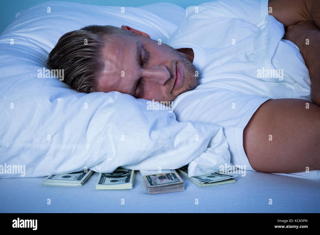 Close-up Of A Man Sleeping With Currency Notes Kept Under His Pillow On Bed Stock Photo