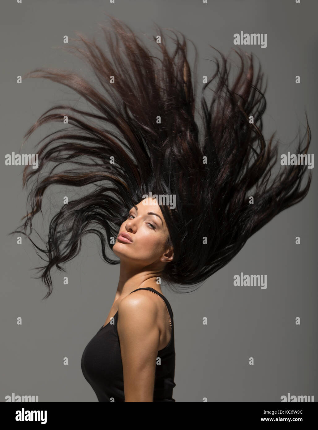 Brunette woman flipping long hair Stock Photo