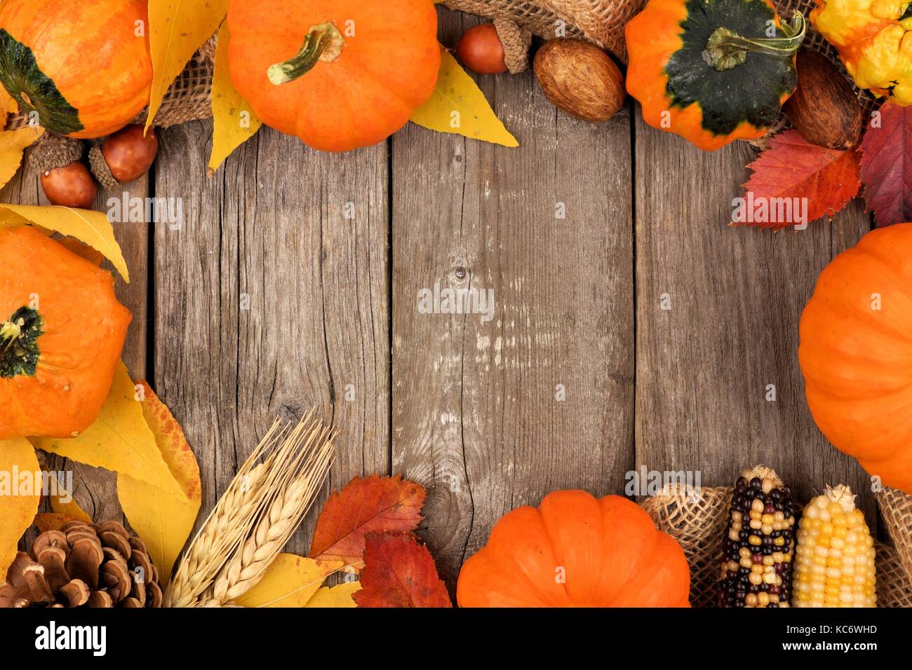 Autumn frame of colorful leaves and pumpkins over a rustic wood background Stock Photo