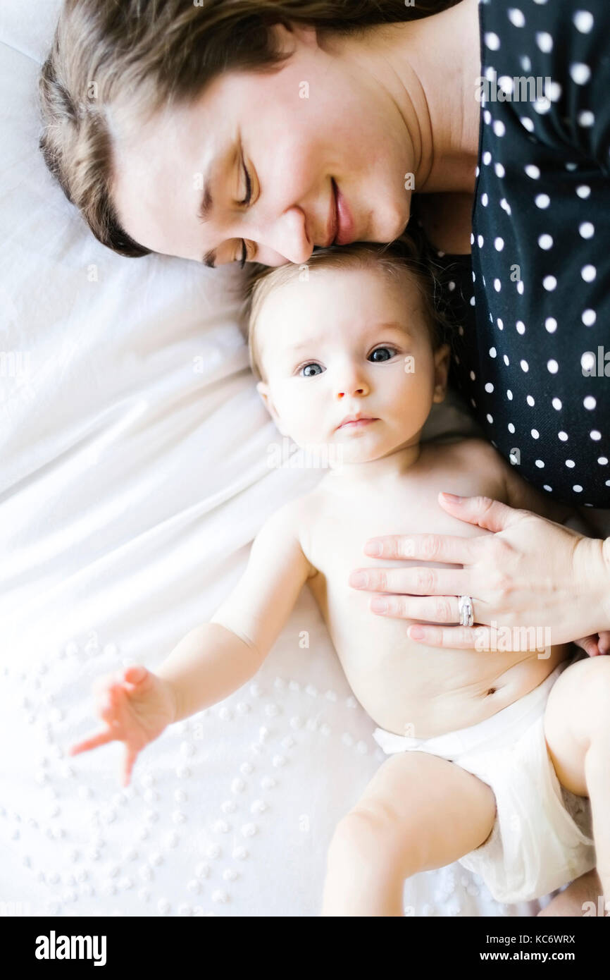 Baby girl (6-11 Months) being hugged by mother, directly above Stock Photo