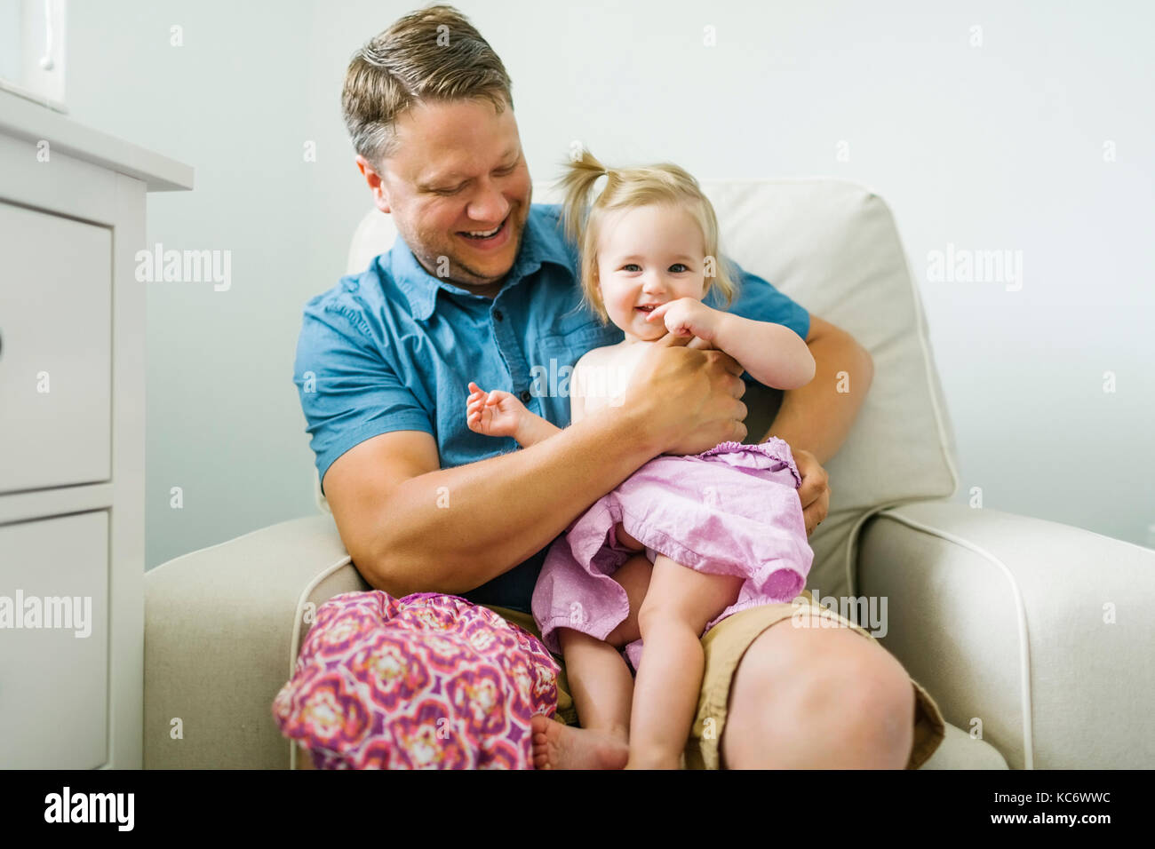 Father with baby girl (12-17 months) sitting in living room Stock Photo
