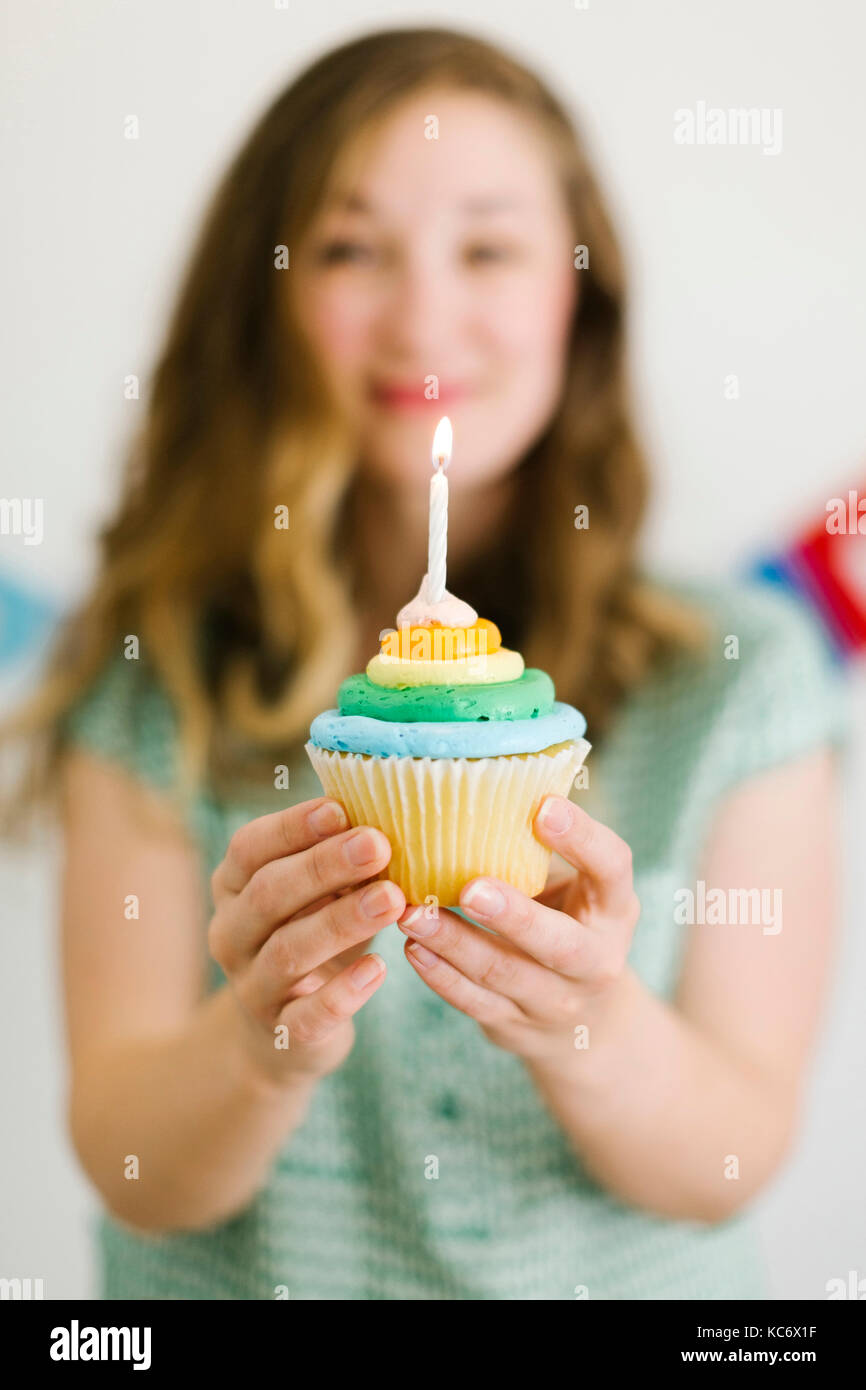Mid adult woman holding cupcake with birthday candle Stock Photo