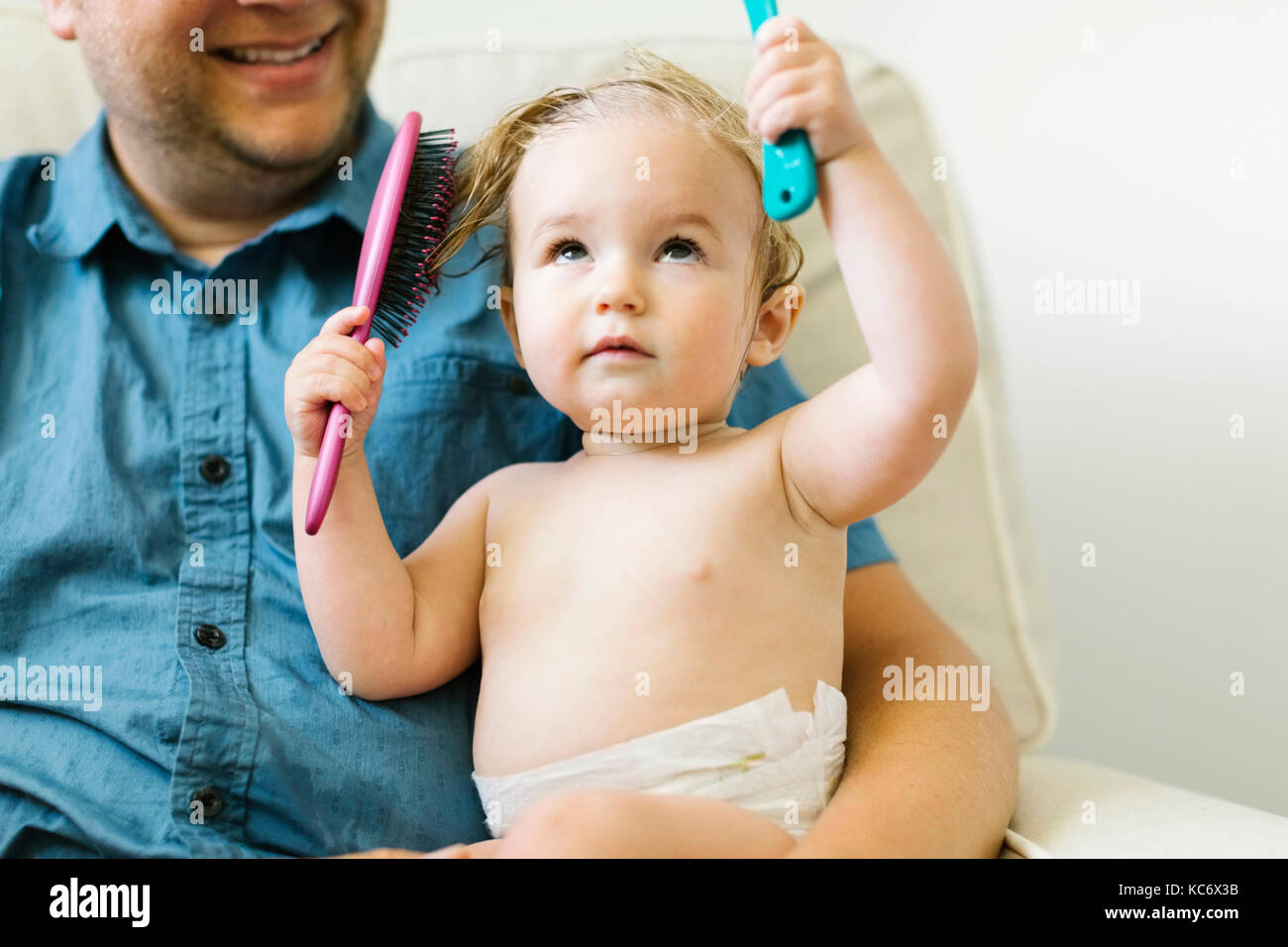 Father and baby girl (12-17 months) brushing hair after bath Stock Photo