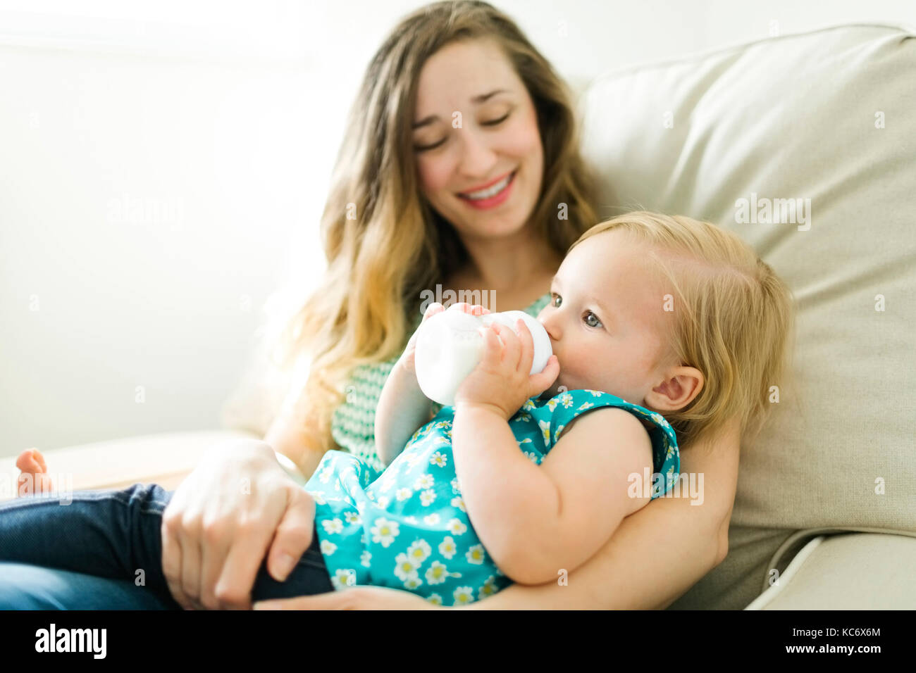 Mother feeding baby girl (12-17 months) in living room Stock Photo