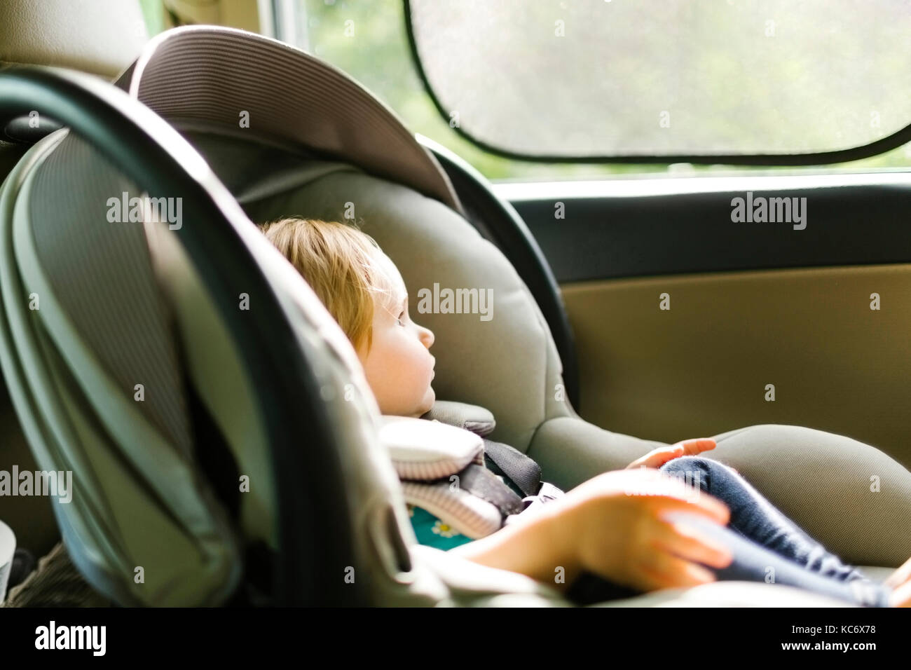 Baby girl (12-17 months) sitting in baby car seat during car trip Stock Photo