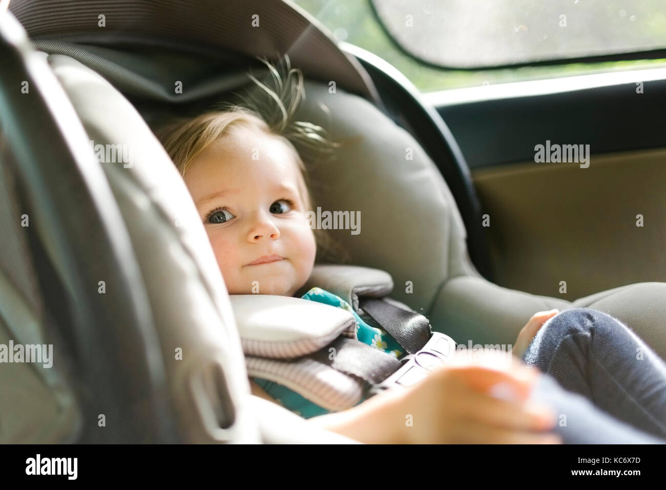 Baby girl (12-17 months) sitting in baby car seat during car trip Stock Photo