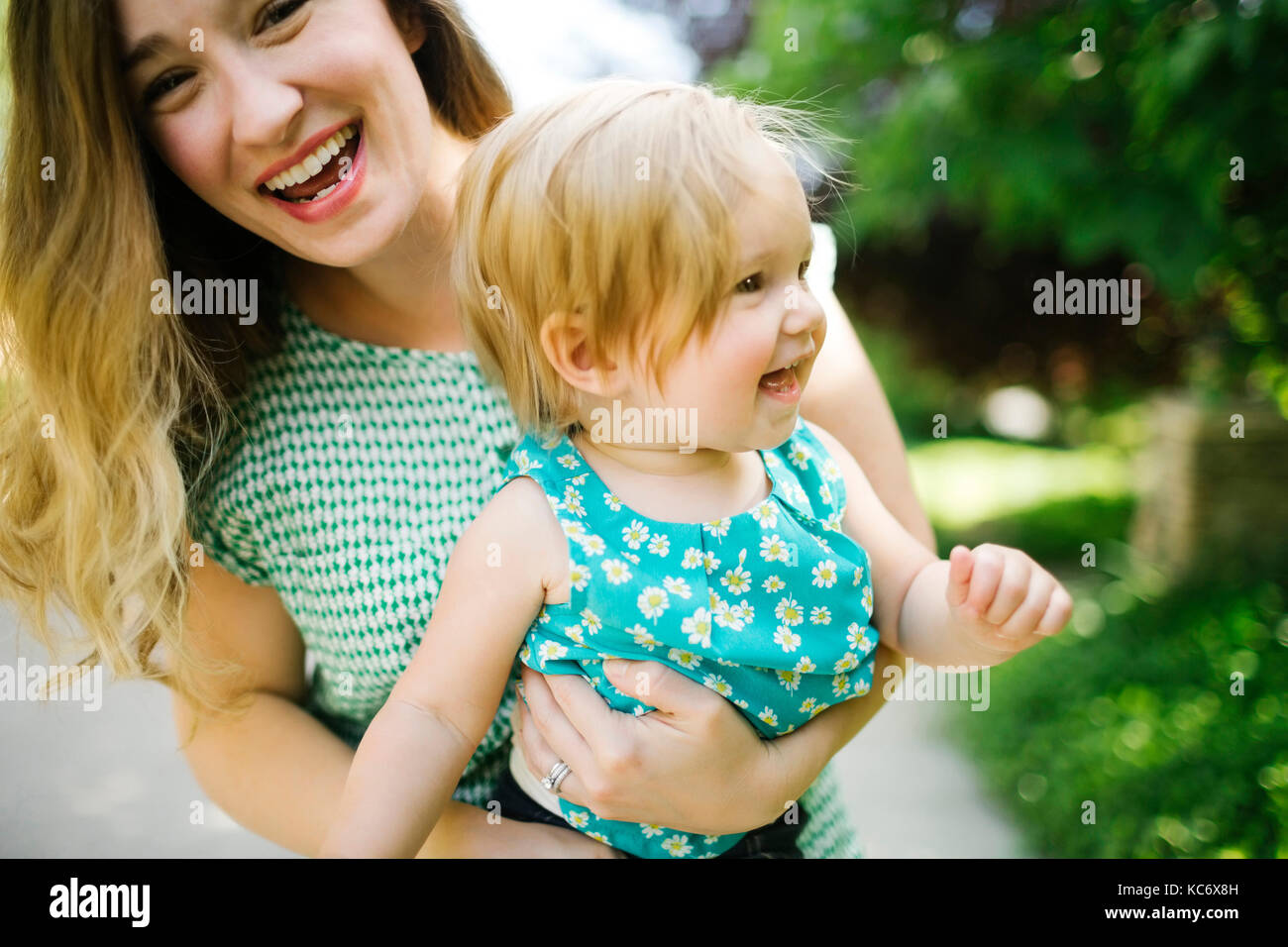 Mother carrying daughter (12-17 months) Stock Photo
