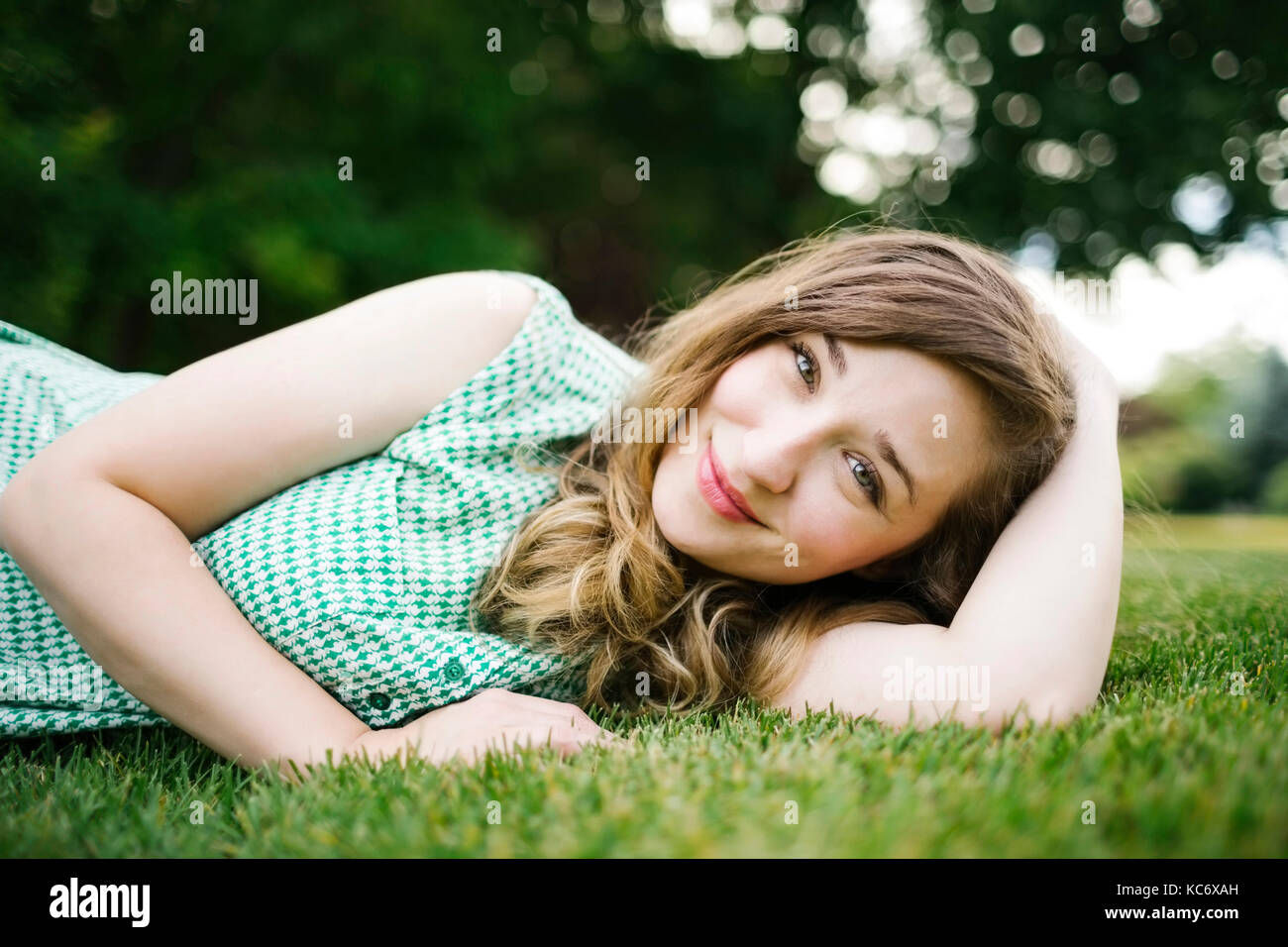 Portrait of woman lying on grass and smiling Stock Photo - Alamy
