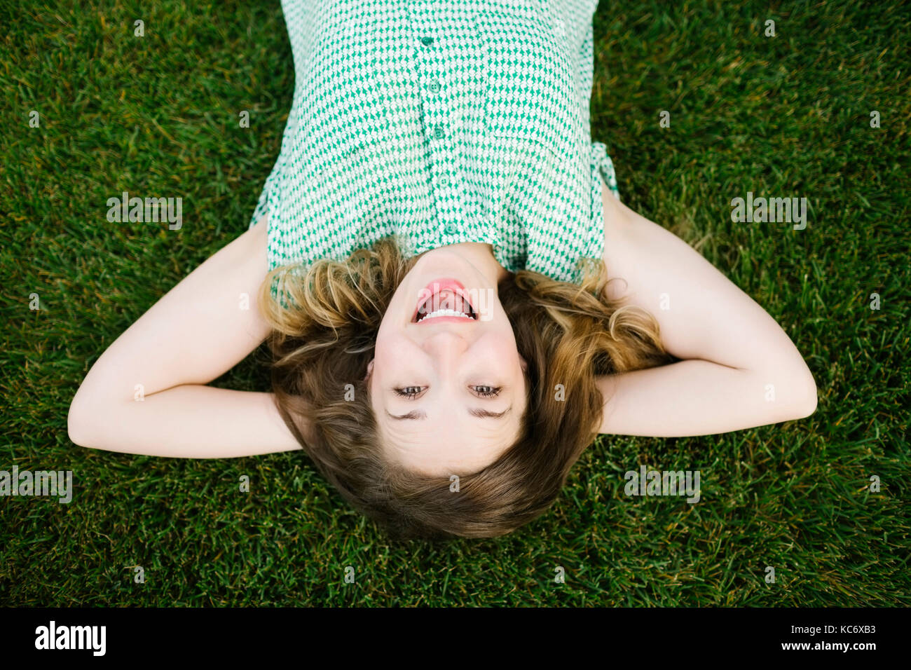 Portrait of woman lying on grass and laughing Stock Photo