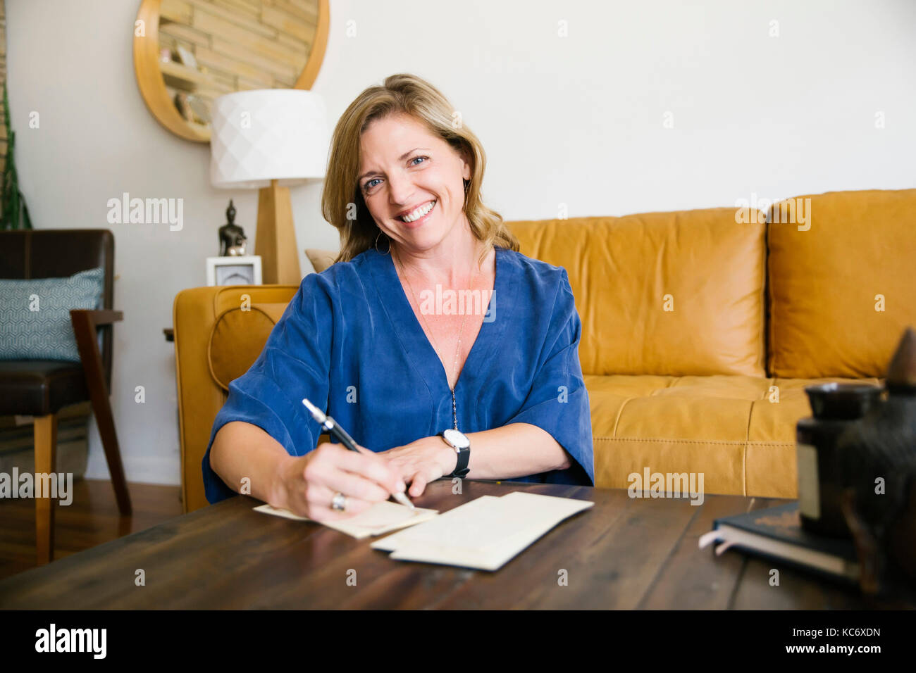 Portrait of woman writing letter in living room Stock Photo