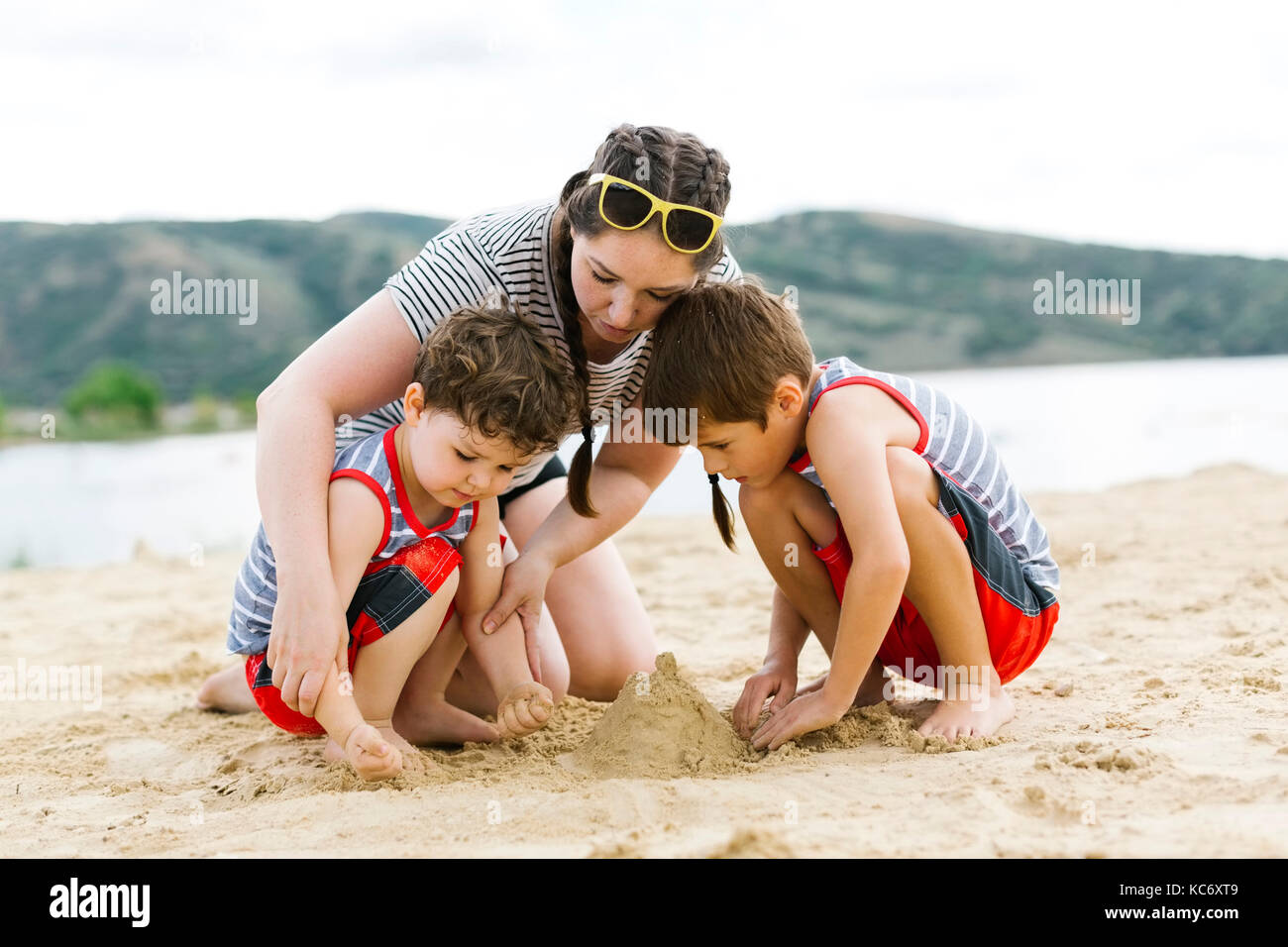 Mother playing with sons (4-5, 6-7) on beach by lake Stock Photo