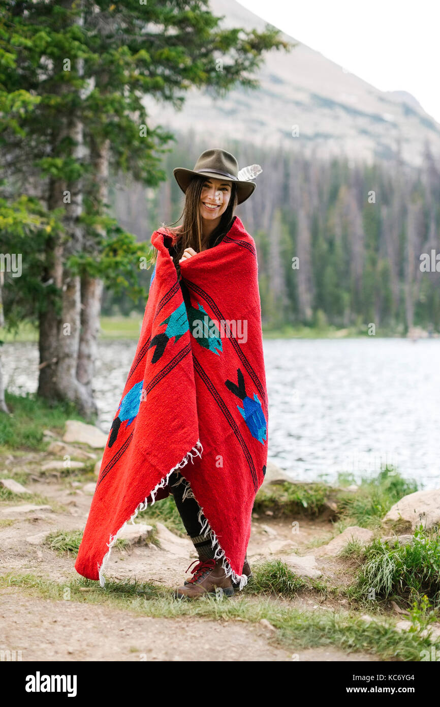 USA, Utah, Midway, Portrait of woman wearing hat and wrapped in blanket while standing by lake Stock Photo