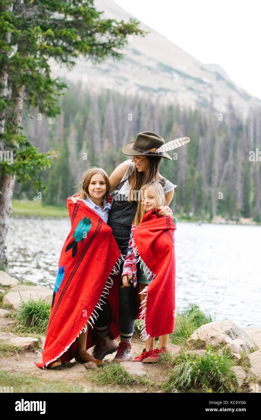 Mother with kids (6-7, 8-9) wrapped in blanket standing by lake Stock Photo