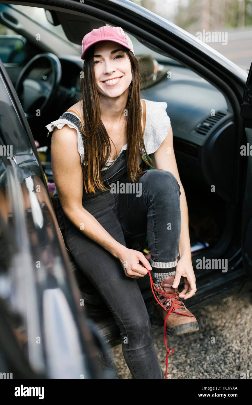 Woman sitting in car and tying shoes Stock Photo