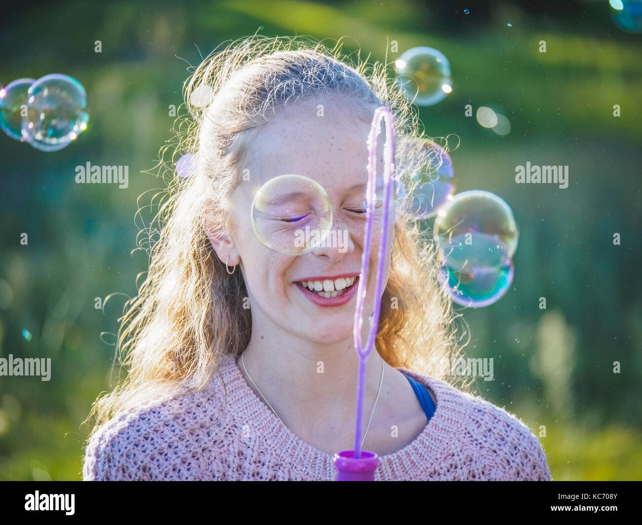 Girl (12-13) blowing bubbles Stock Photo