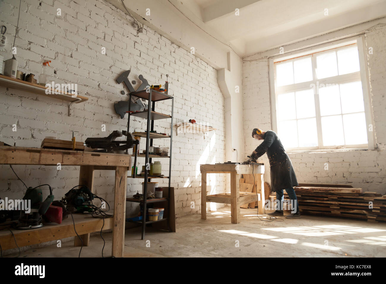 Spacious workshop interior with handyman working with power tool Stock Photo