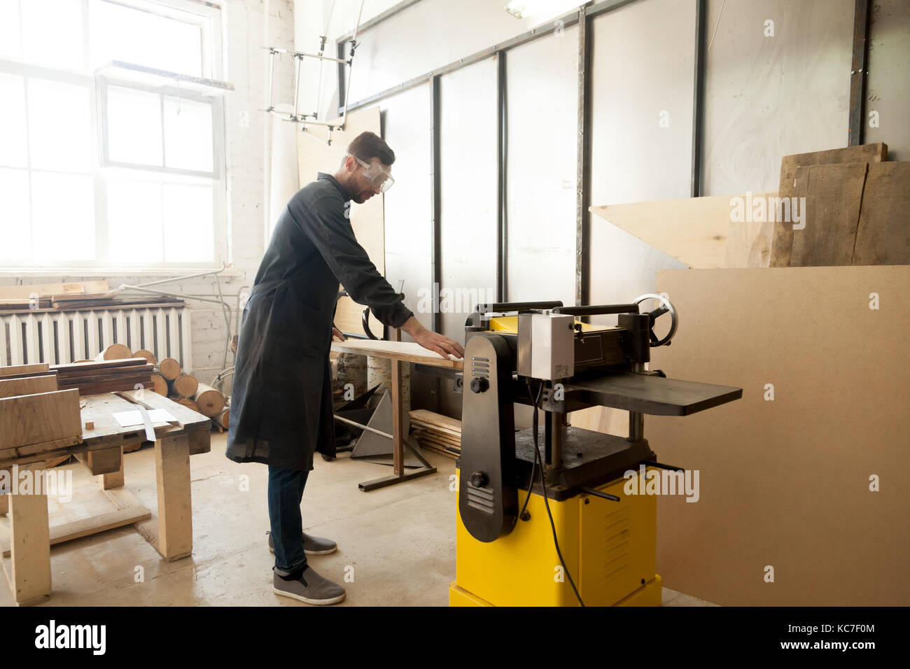 Jointer in protective workwear processing wood on stationary pow Stock