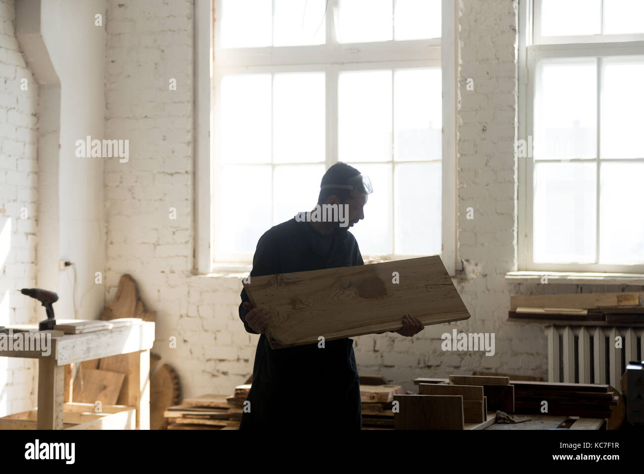 Young carpenter holding wooden board, woodworking in carpentry s Stock Photo