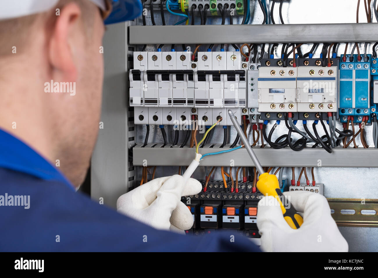 Male Electrician Working On Fusebox With Screwdriver Stock Photo
