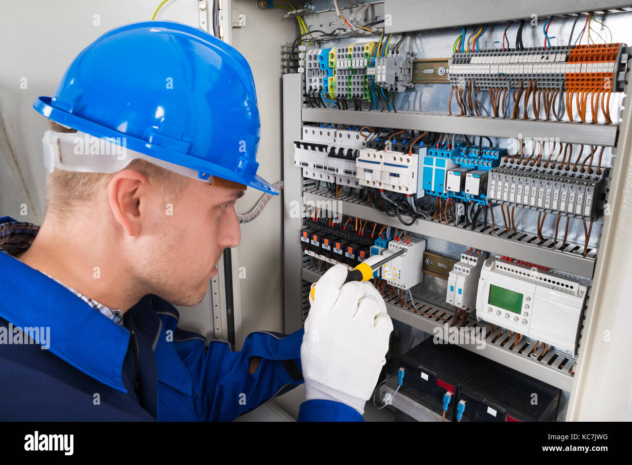 Male Electrician Working On Fusebox With Screwdriver Stock Photo