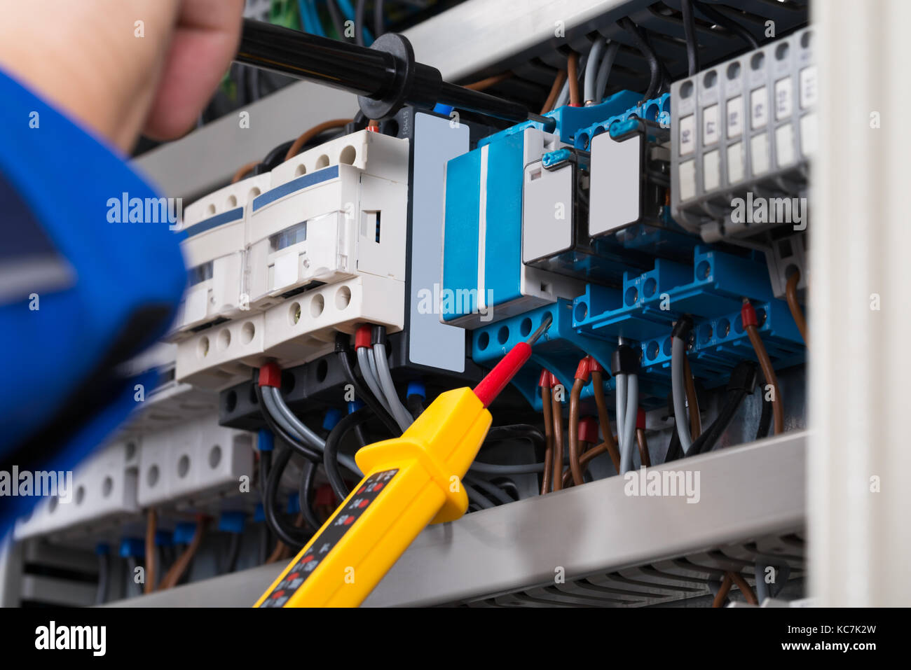 Male Electrician Examining Fusebox With Voltage Tester Stock Photo