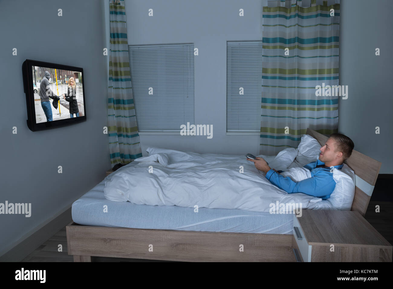Photo Of Man Lying On Bed Watching Television Stock Photo