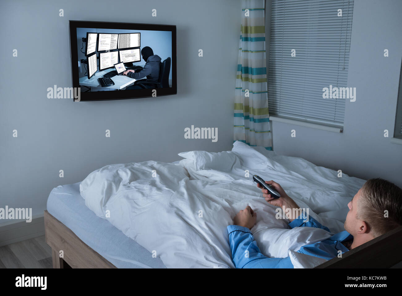 Young Man Lying On Bed Watching Television In His Living Room Stock Photo