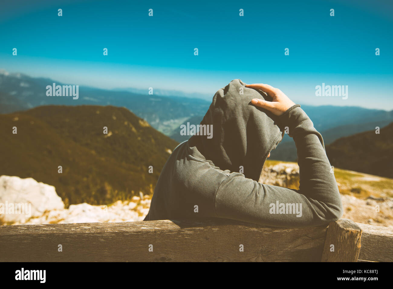 Depressed sad woman at high mountain viewpoint. Female person in hoodie thinking about problems in life. Toned image. Stock Photo