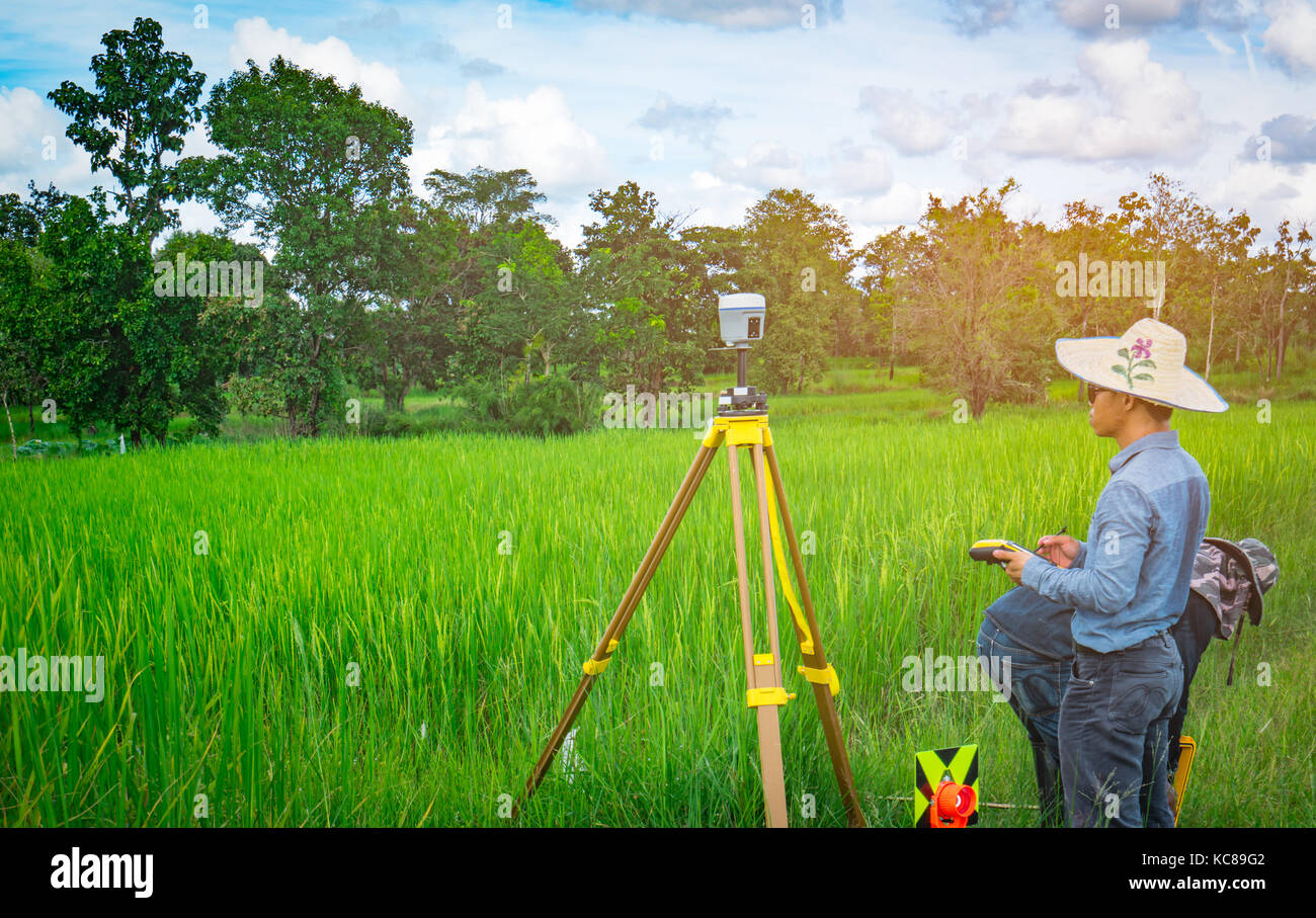 UBONRATCHATHANI, THAILAND-SEPTEMBER 26, 2017 : Asian smart engineer or surveyor is working on controller screen for surveying land in rice field. GPS  Stock Photo