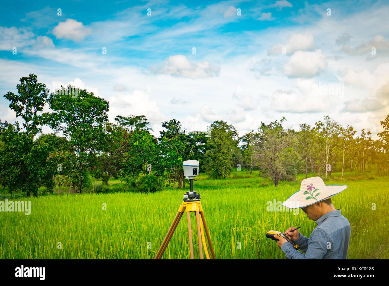 UBONRATCHATHANI, THAILAND-SEPTEMBER 26, 2017 : Asian smart engineer or surveyor is working on controller screen for surveying land in rice field. GPS  Stock Photo