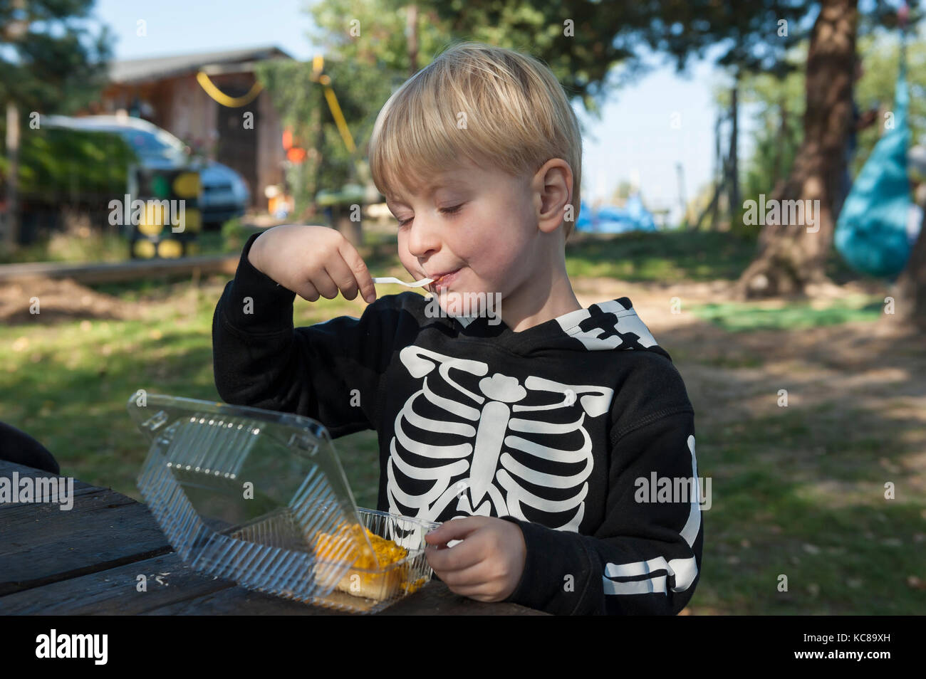 Boy in skeleton costume eating pumpkin pie Stock Photo