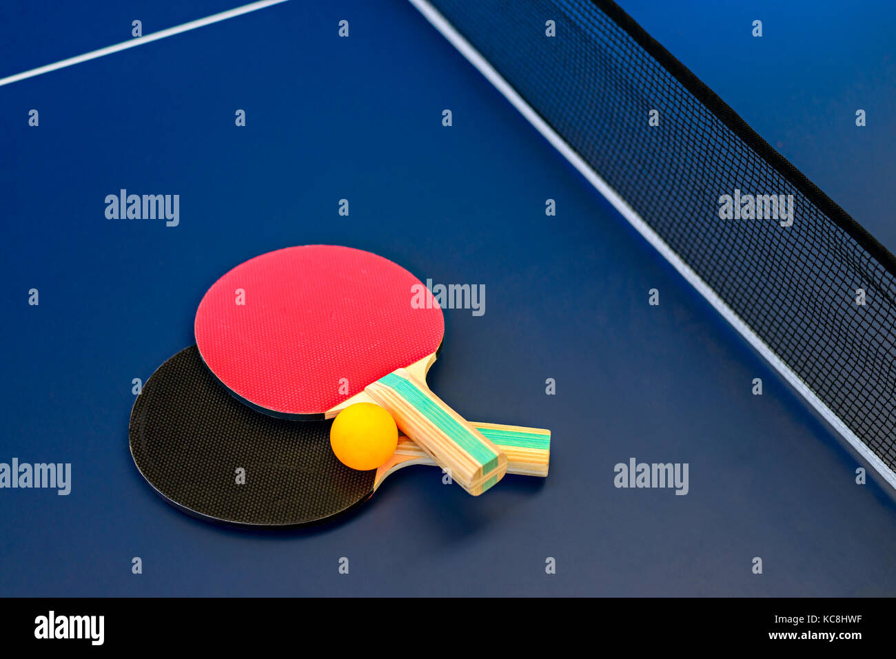 Table tennis table with rackets, net and orange ball Stock Photo