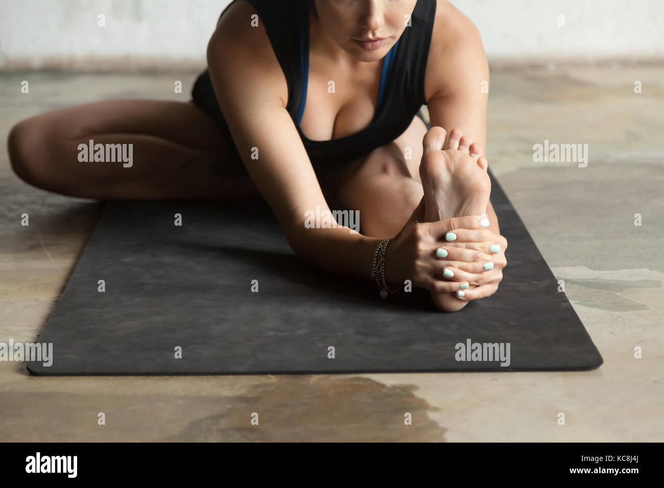 Young sporty woman in Janu Sirsasana pose, studio background Stock Photo