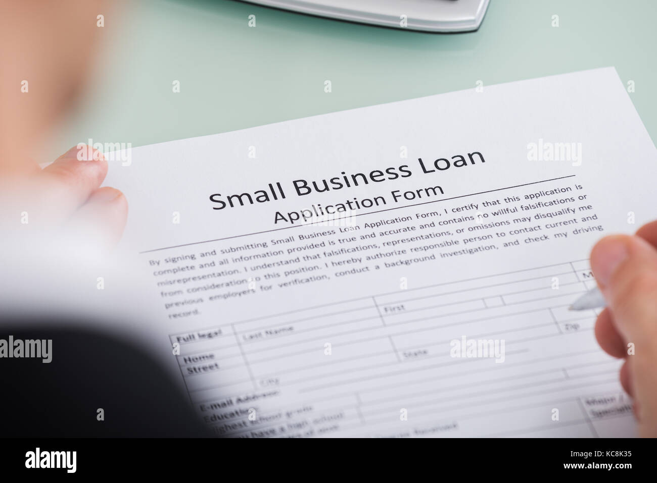 Close-up Of Person Hand Over Small Business Loan Application Form Stock Photo