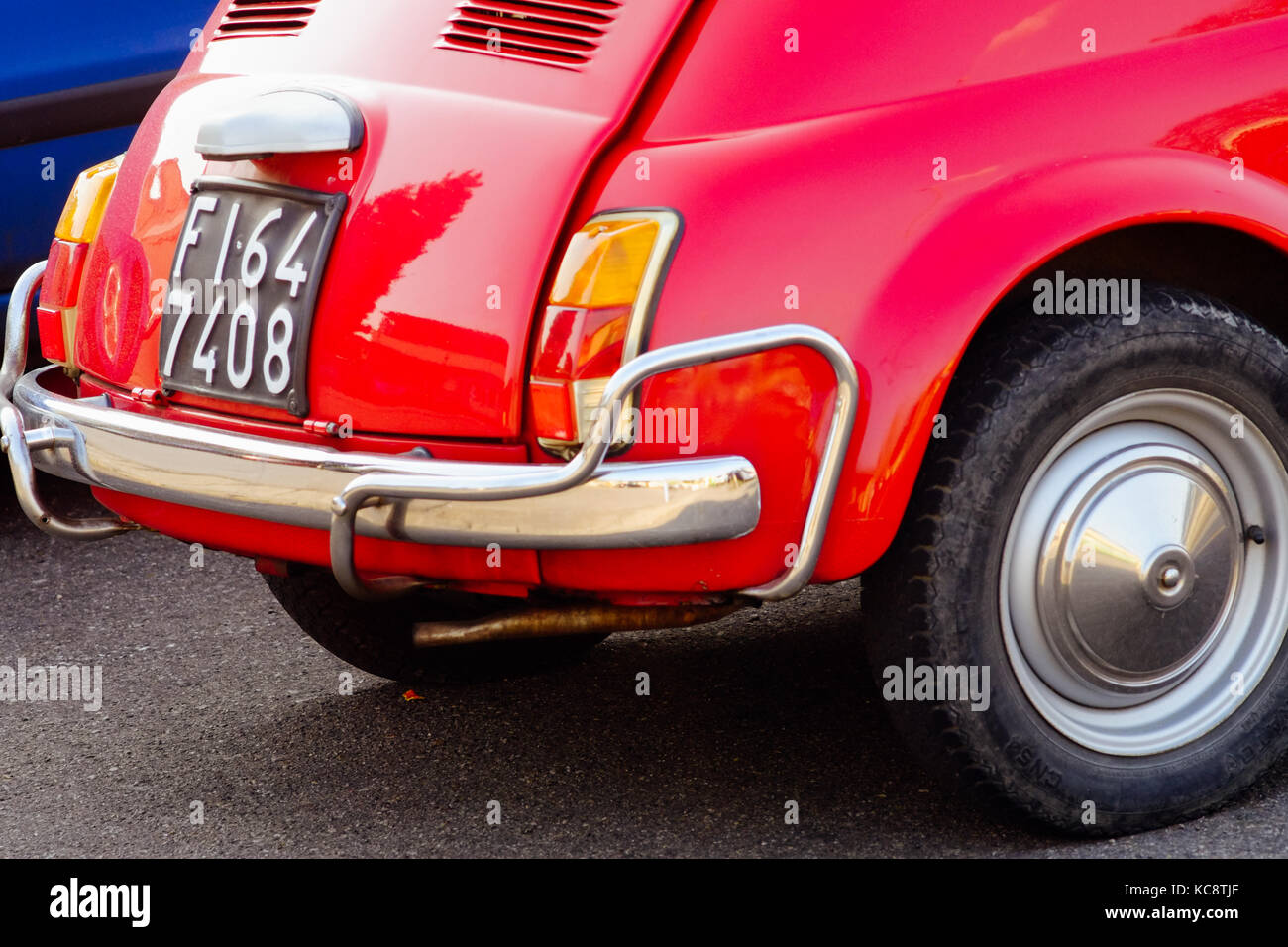 Red Fiat 500 parked near blue cars on the street. Classic vintage model ...