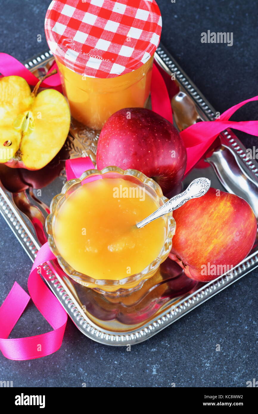 Homemade apple marmalade in a glass bowl and in a glass jar on a grey